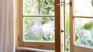 A window with a wooden frame and a view of greenery outside. - Church Accommodation (Hahei)