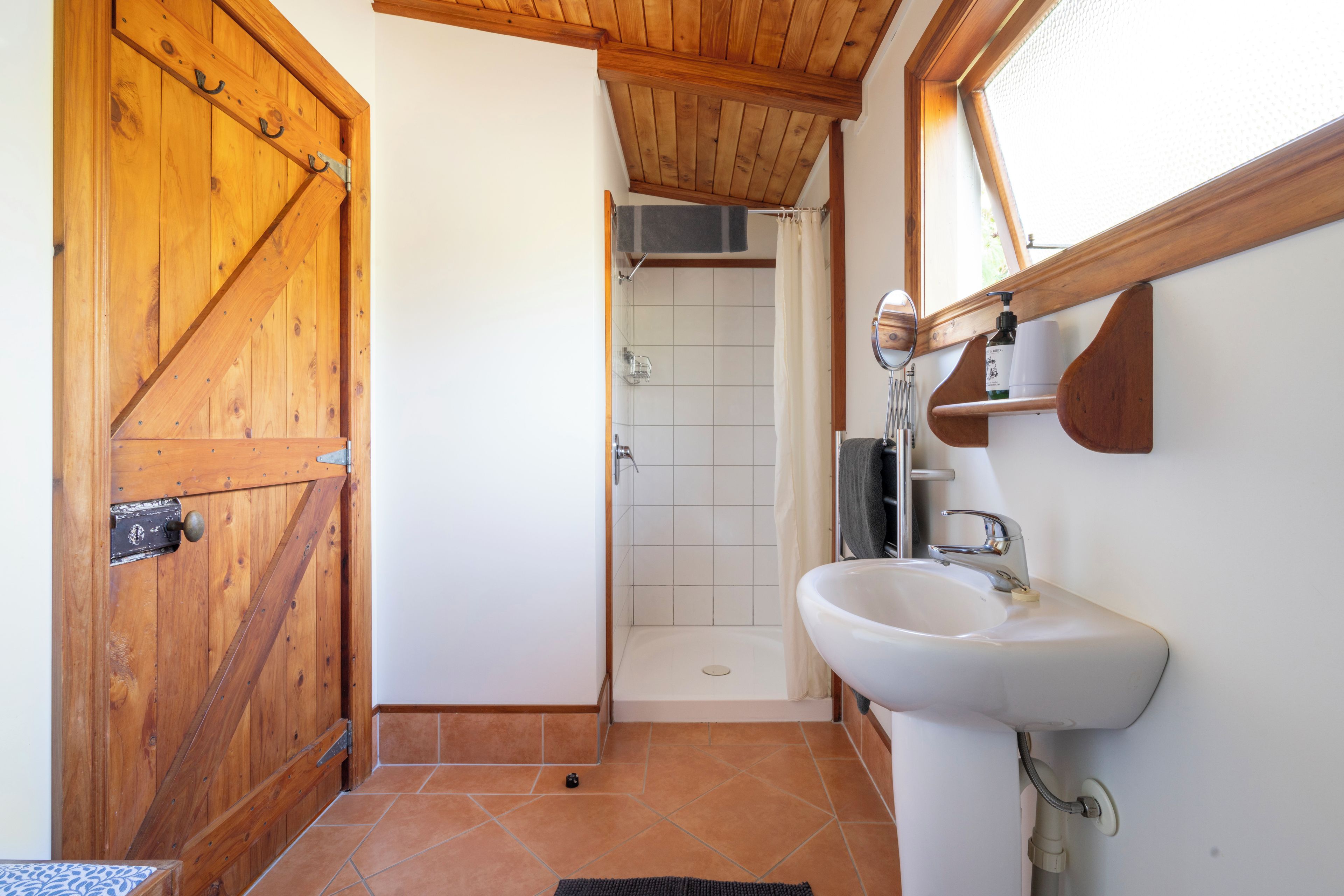 Une salle de bain avec une porte en bois, un lavabo et une douche.