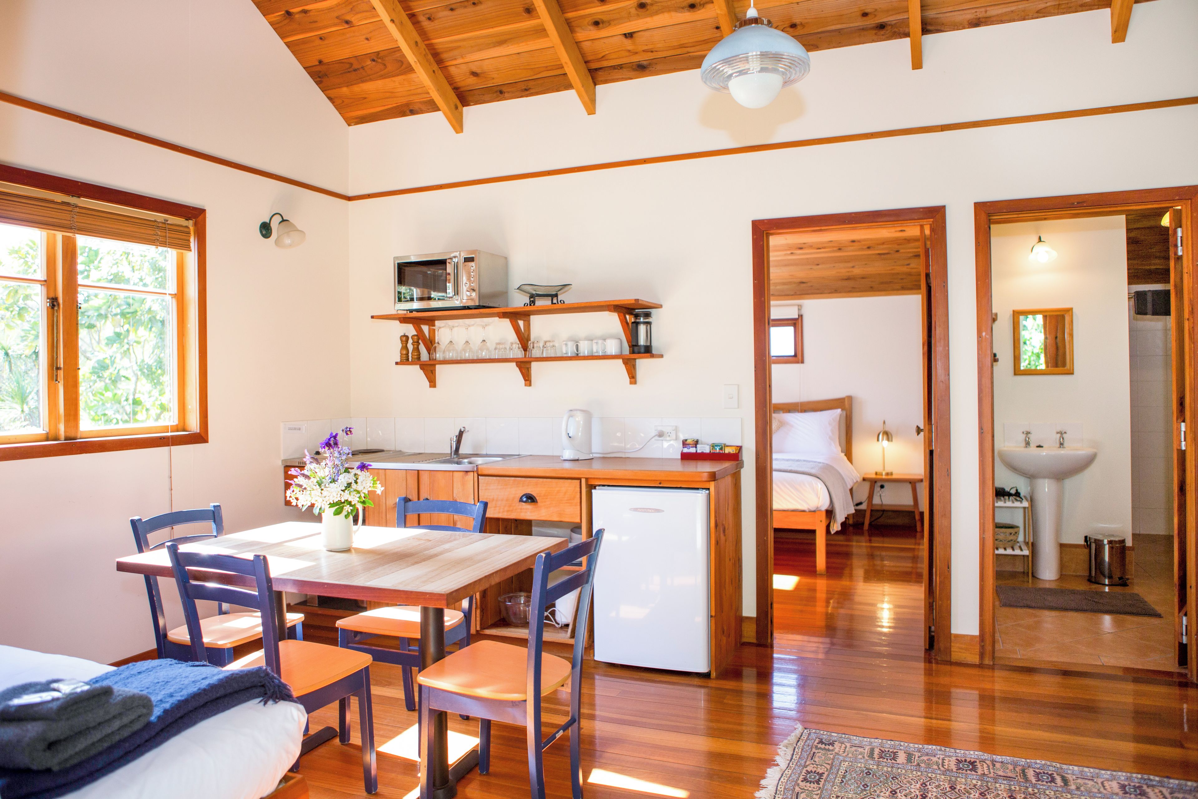 Cocina compacta con comedor, suelo de madera y vista hacia un dormitorio.