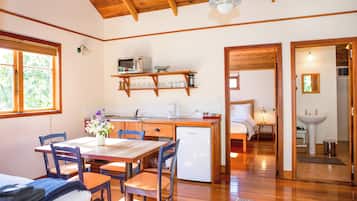 Cocina compacta con comedor, suelo de madera y vista hacia un dormitorio.