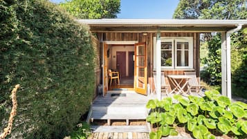 Una pequeña cabaña de madera con un porche, una puerta y una ventana.