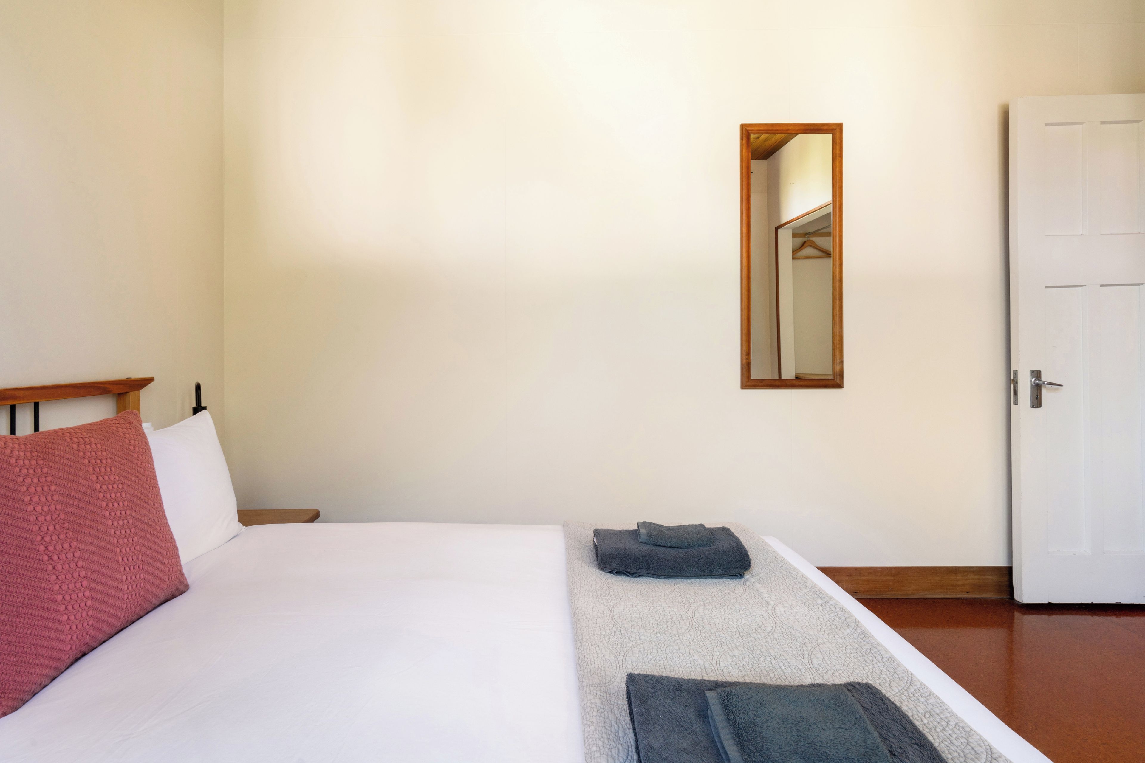 Un dormitorio con una cama, una mesita de noche, un espejo y una puerta.