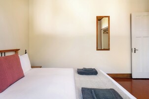 Un dormitorio con una cama, una mesita de noche, un espejo y una puerta.