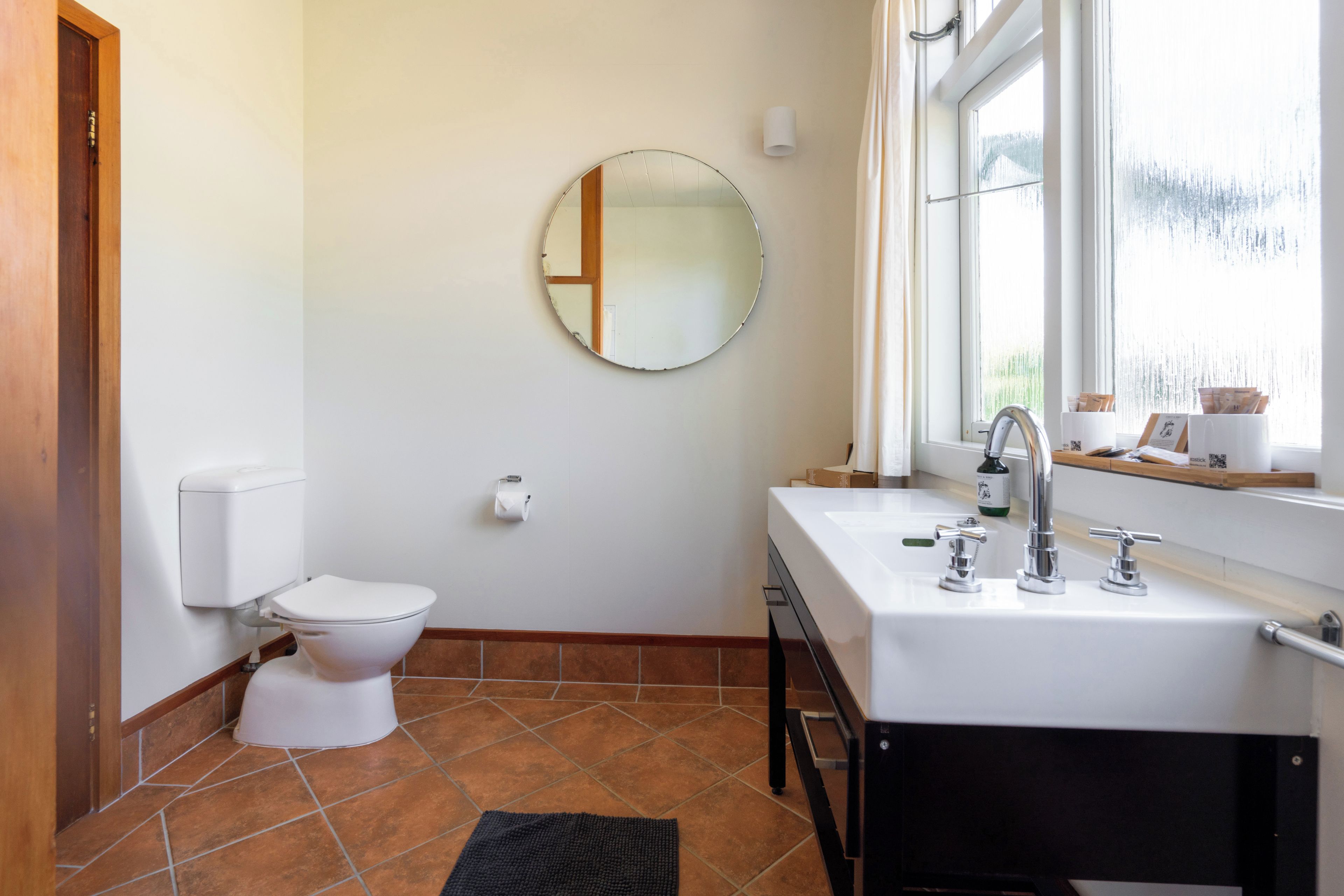 Ein Badezimmer mit Toilette, Waschbecken, Spiegel und Fenster.