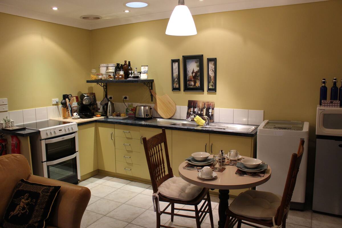 A compact kitchen with a dining area, equipped with a stove, oven, refrigerator, and various kitchen appliances.