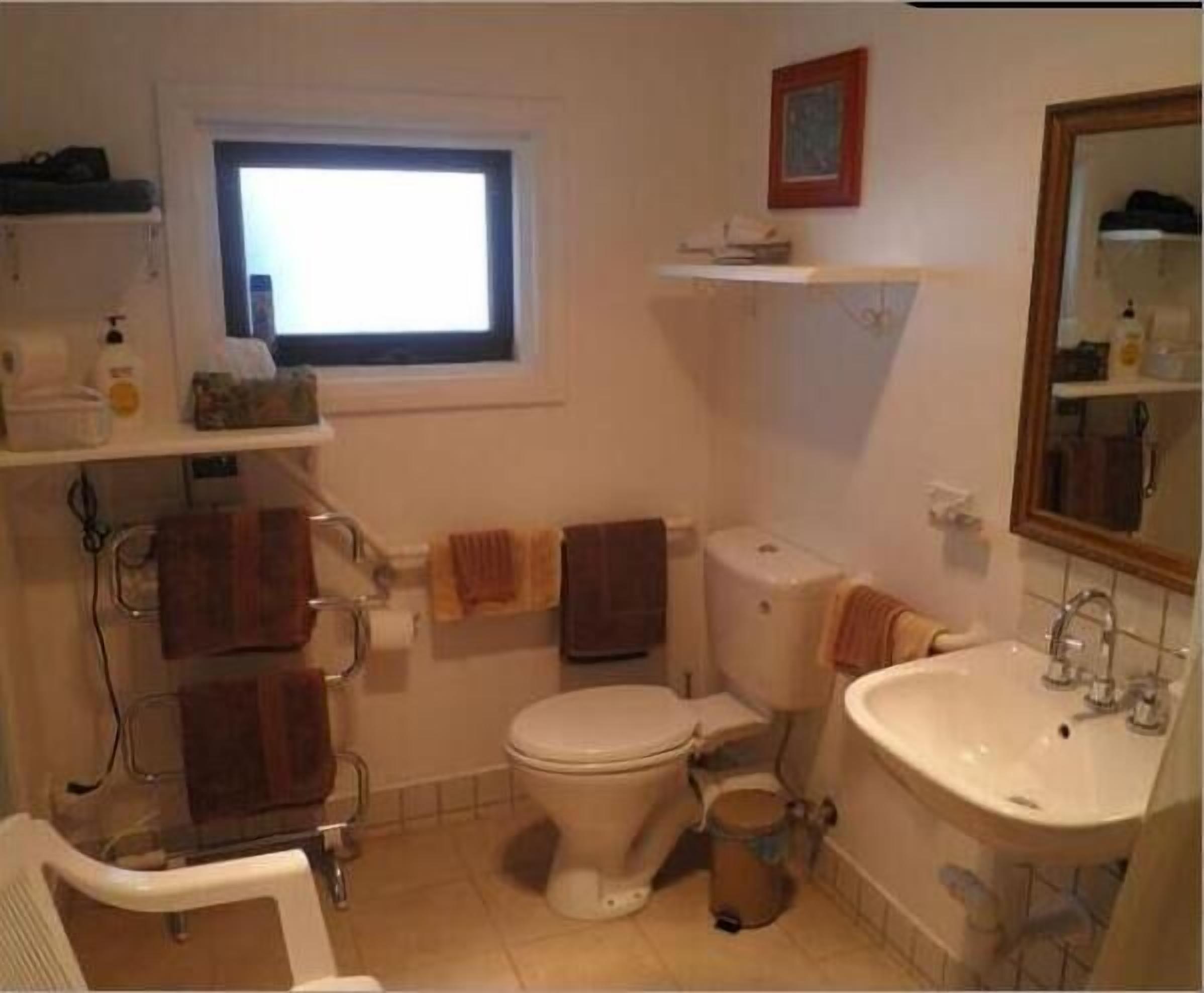 Un baño con inodoro, lavamanos y ventana.