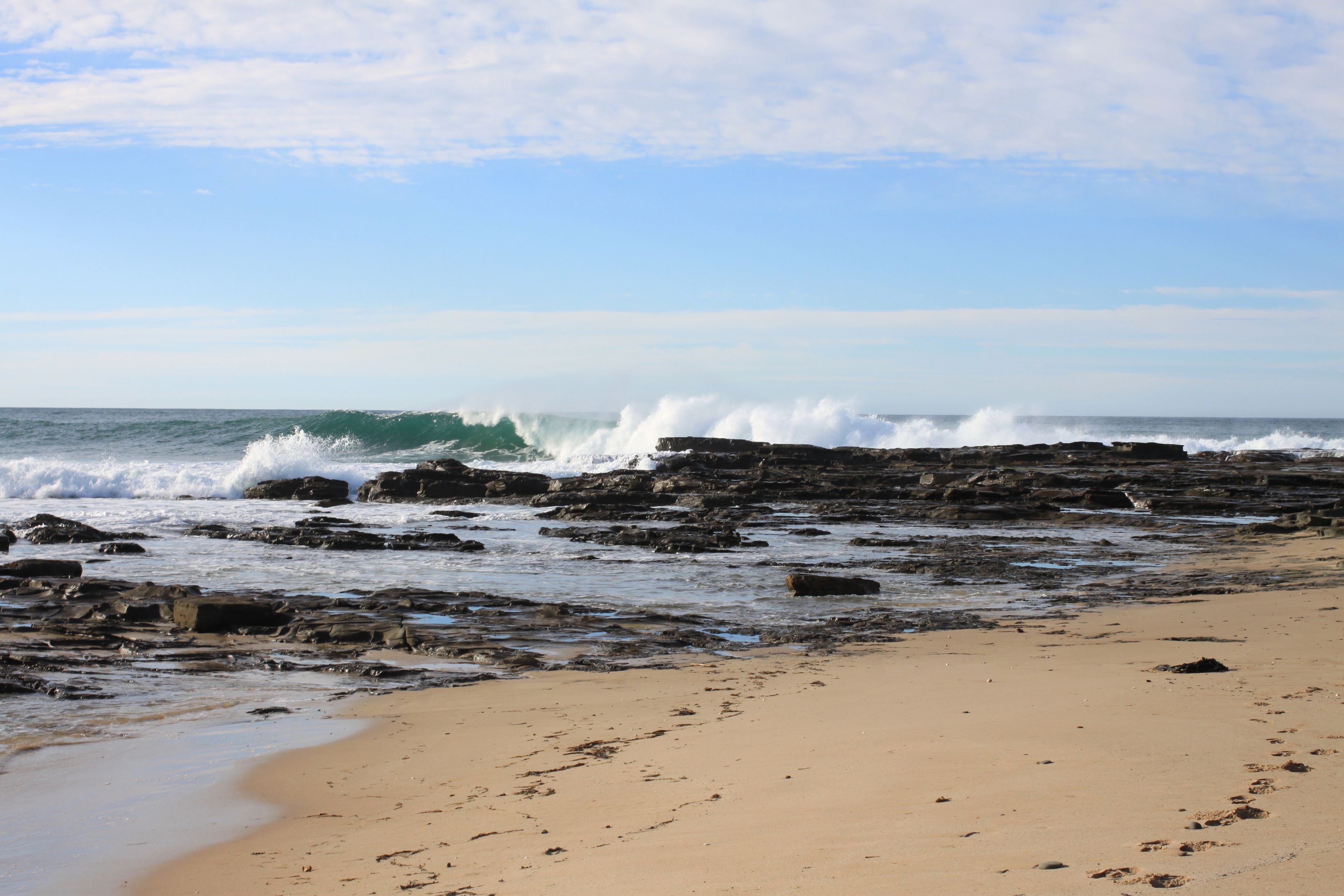 A rocky beach with waves crashing against the shore.