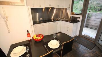 A modern kitchen with white cabinets, a black countertop, and a dining area set for two.