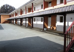 A motel with a covered parking area, multiple rooms with individual entrances, and a brick facade. - Canberra Lyneham Motor Inn (Lyneham)