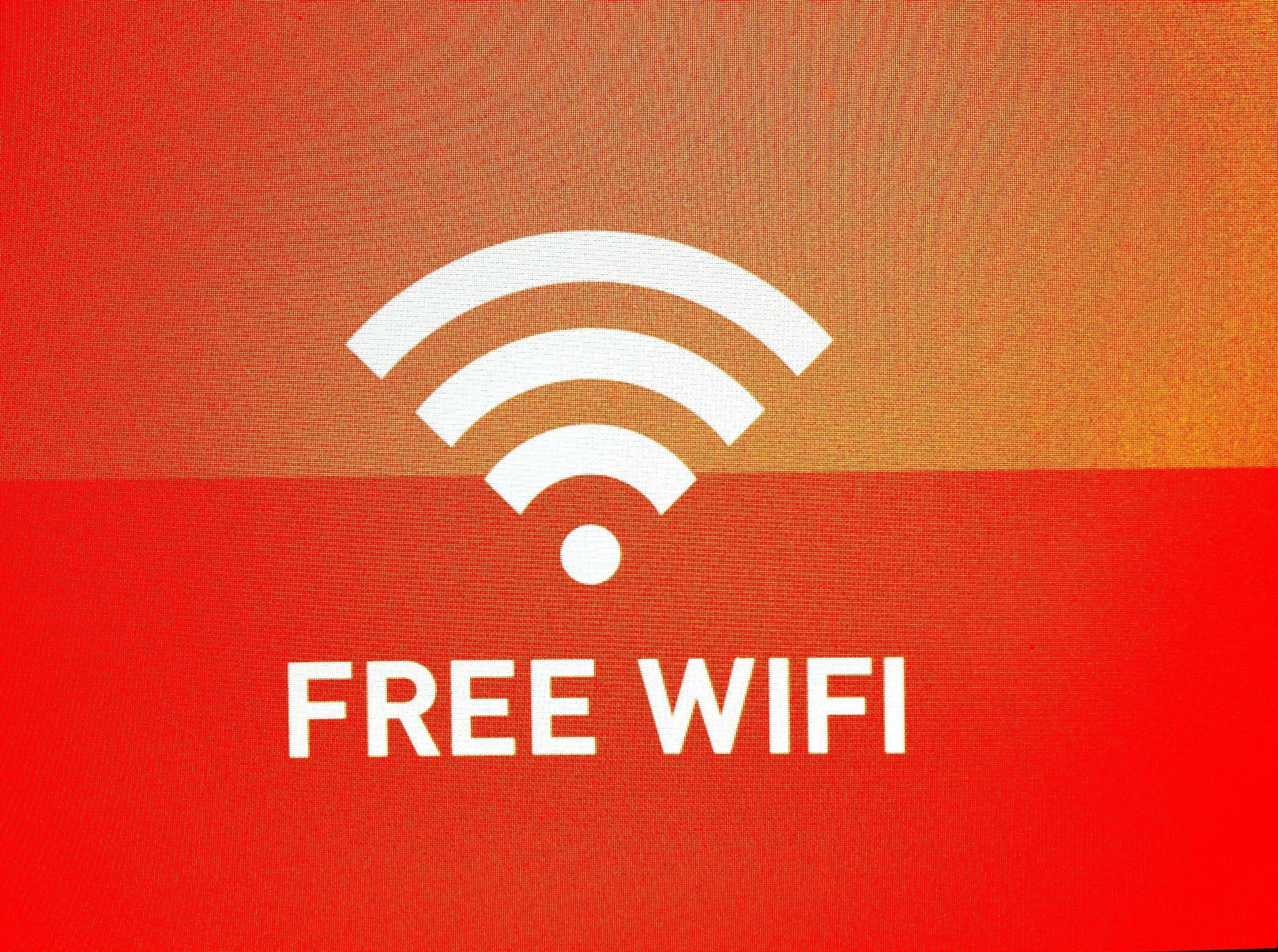 Un fond rouge avec un symbole Wi-Fi blanc et le texte « WI-FI GRATUIT ».