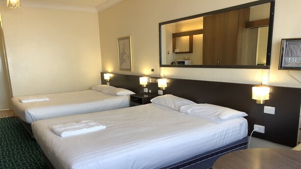 Una habitación de hotel con dos camas, una mesa redonda y un espejo grande.
