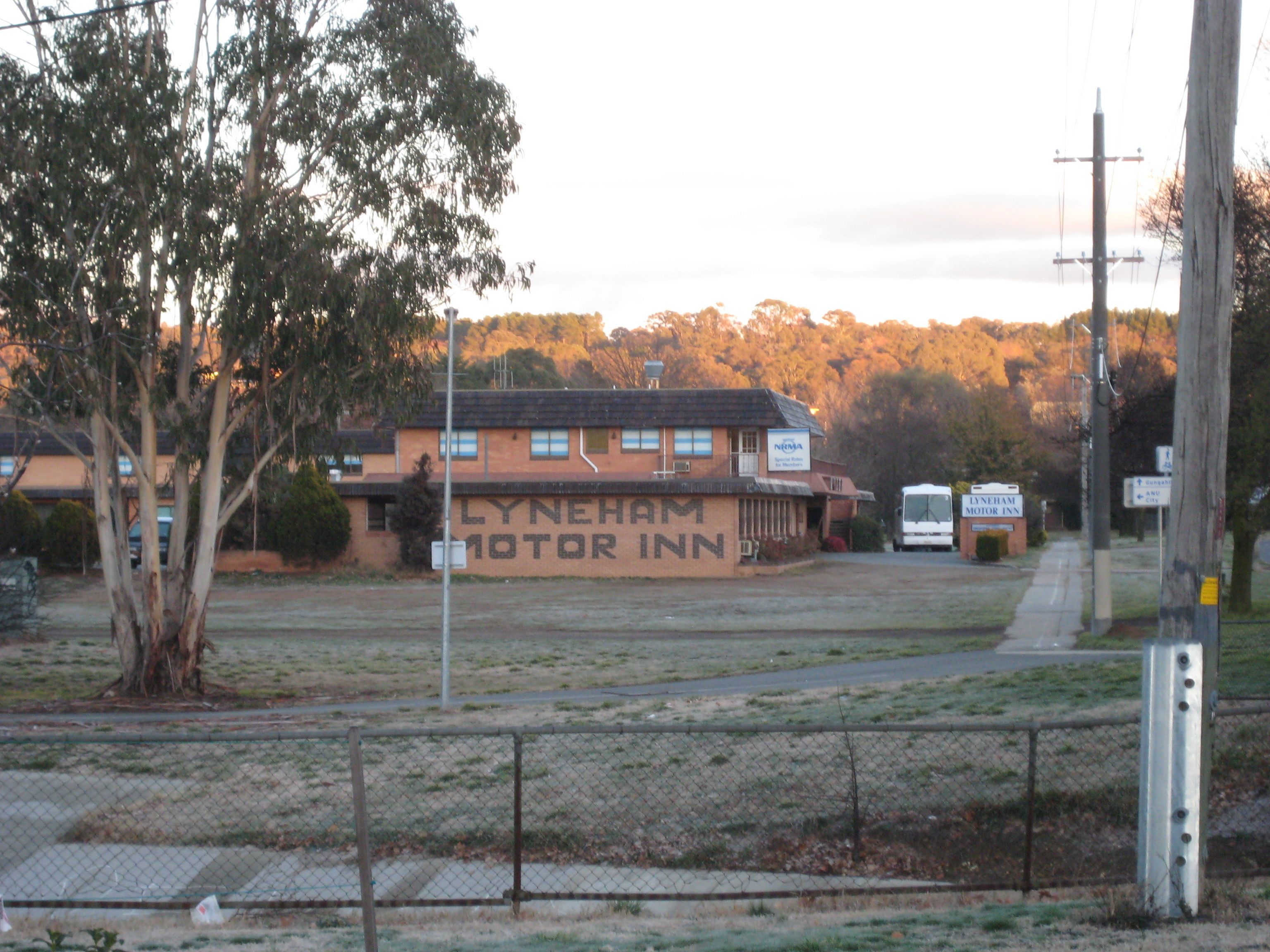 A motel with a sign reading "LYNEHAM MOTOR INN" and a fenced parking area.