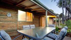 A wooden cabin with a glass table and chairs, a window, and a door. - Bayplay Beach Accommodation - 2 locations (Portsea)