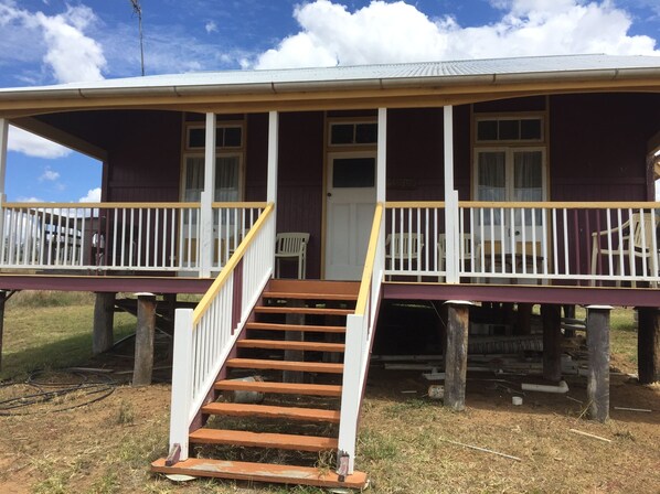 A two-story house with a porch, wooden stairs, and a door.