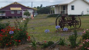 A rural setting with two houses, one purple and one white, and a horse-drawn carriage in a flower-filled field. - Rangemore Estate (Moola)