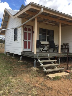 A small house with a porch, a red door, and a window.