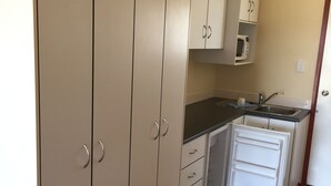 A compact kitchen with beige cabinets, a microwave, a sink, and a refrigerator. - Rangemore Estate (Moola)