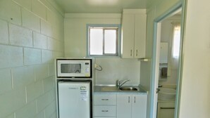 A compact kitchen with a microwave, refrigerator, sink, and cabinets. - Hatton Vale Motel (Hatton Vale)