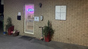 A brick building with a neon 'OPEN' sign, a map on the wall, and a scooter parked outside. - Hatton Vale Motel (Hatton Vale)