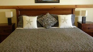Una cama con una colcha estampada, dos almohadas con diseños de estrellas y una obra de arte enmarcada encima.