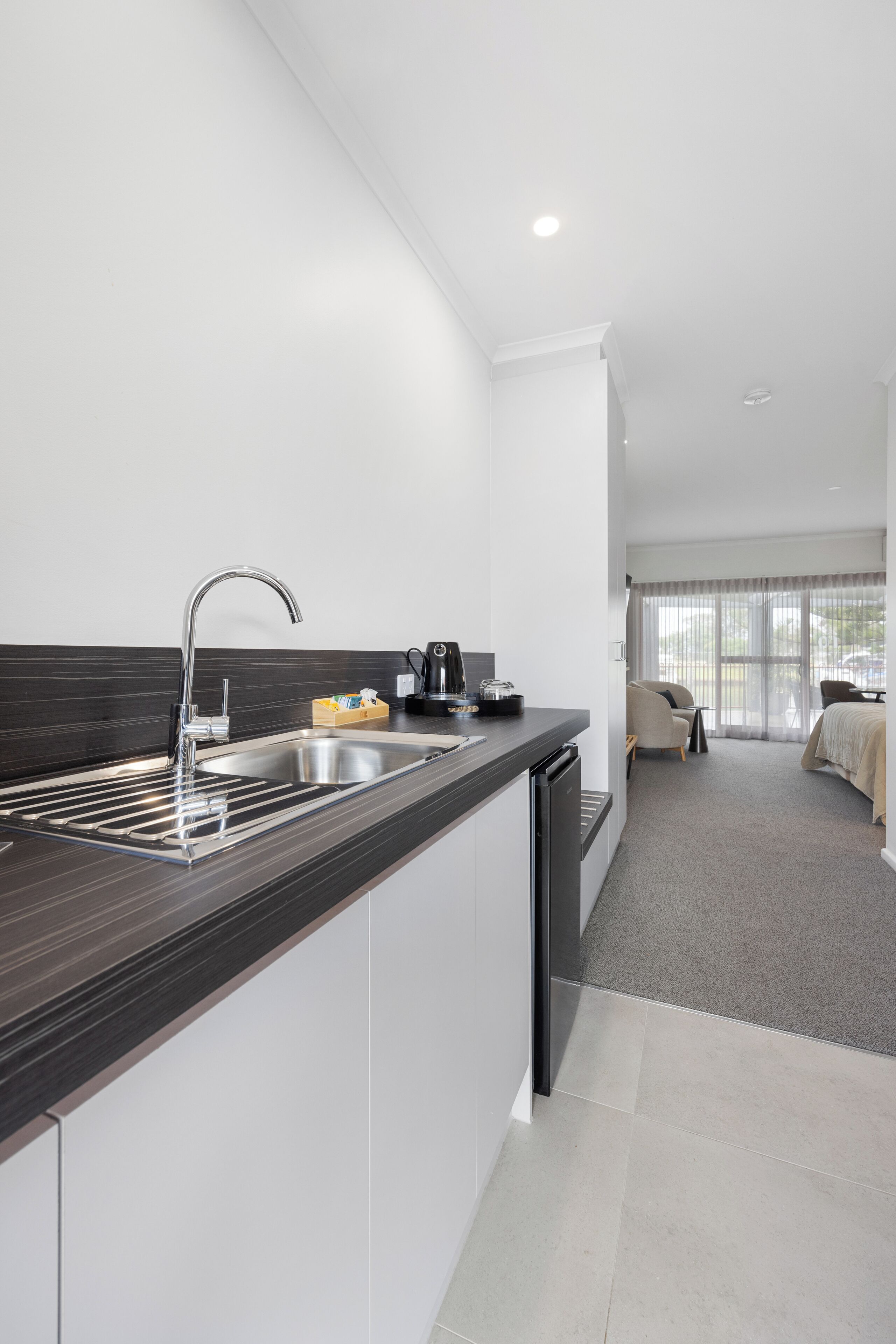A modern kitchen with a stainless steel sink and a coffee machine.