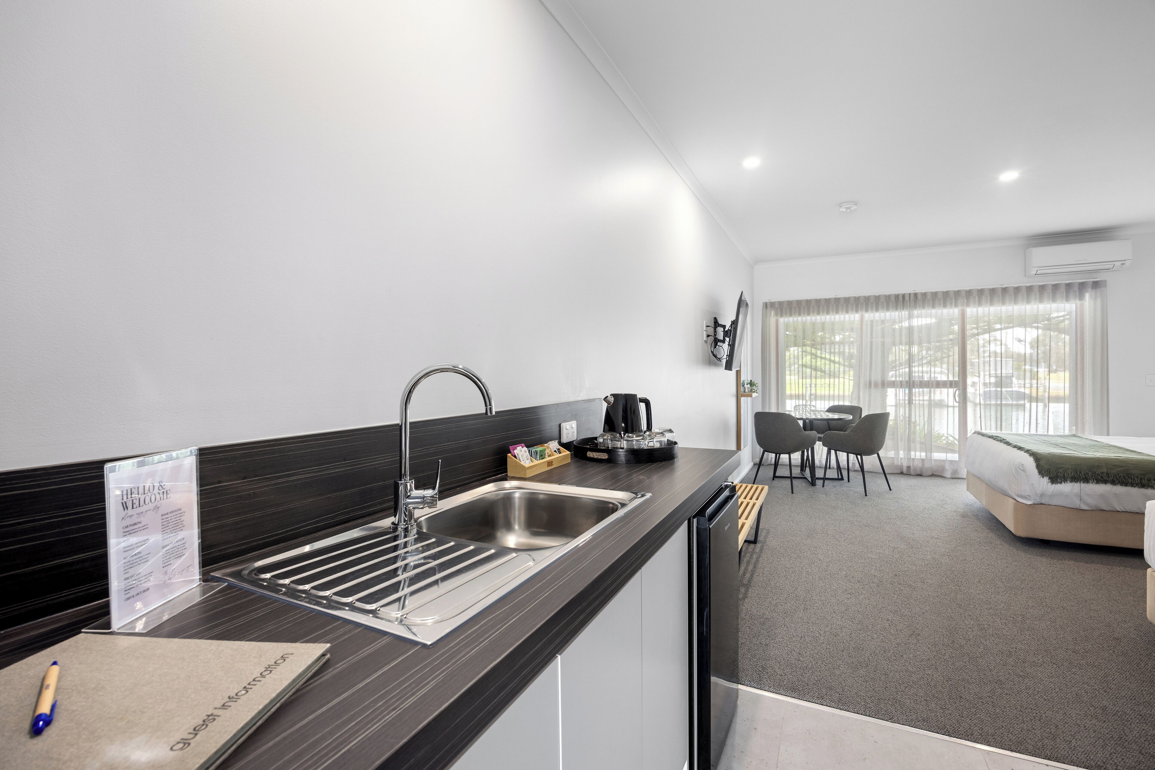 Une chambre d’hôtel moderne dotée d’un coin cuisine, d’une table à manger et d’un lit.
