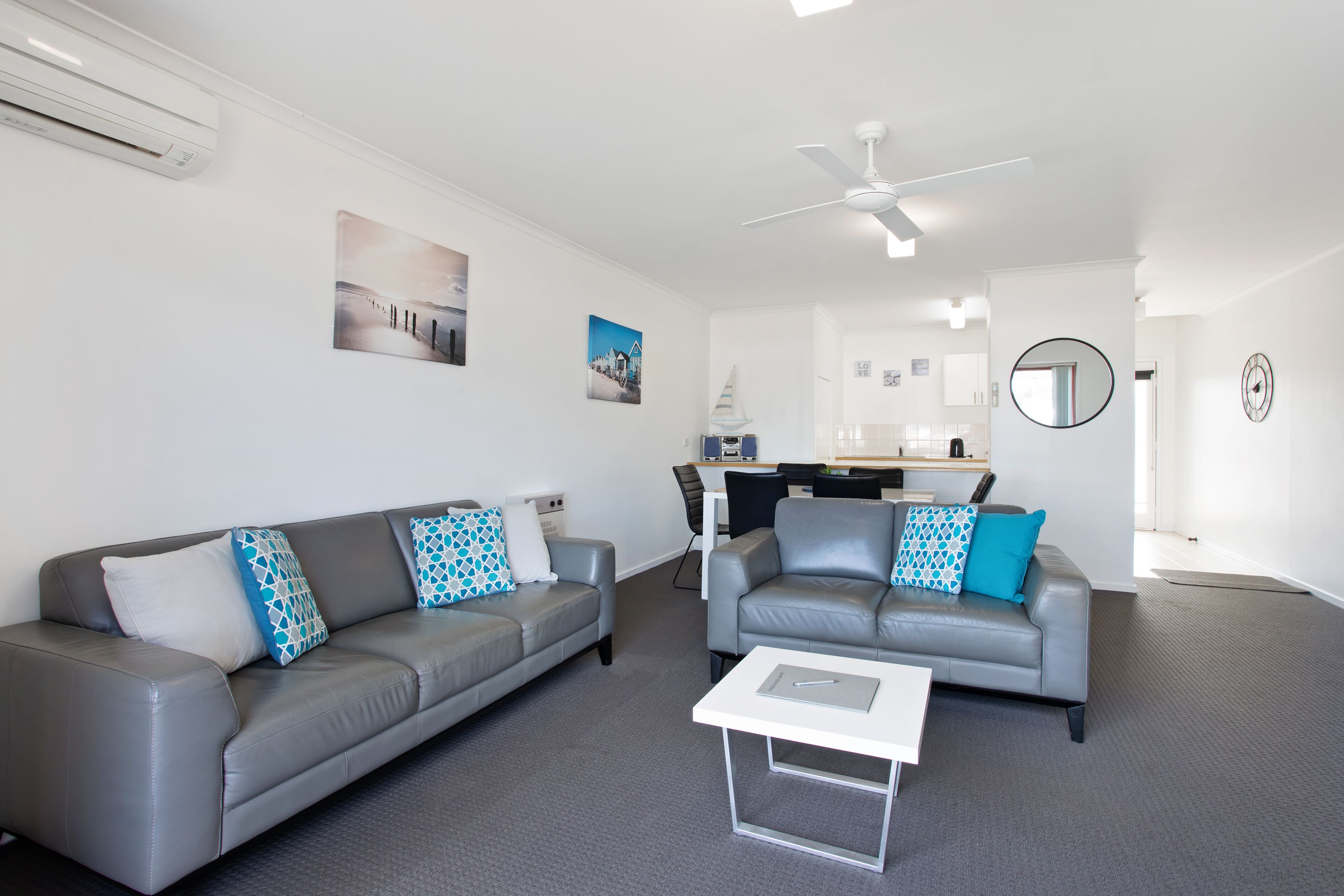 A modern living room with two grey sofas, a white coffee table, and a ceiling fan.