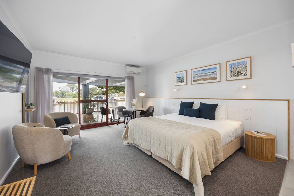 Una habitación de hotel con cama, una silla, una mesa y vistas al exterior.
