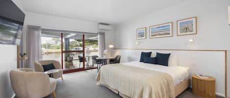 Ein Hotelzimmer mit Bett, Stuhl, Tisch und Blick ins Freie.