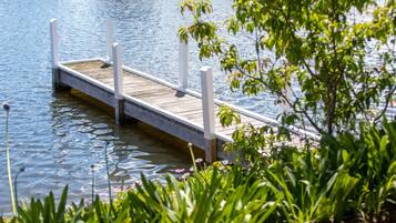 A wooden dock extending into calm water, surrounded by lush greenery.