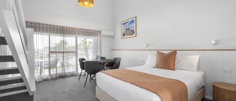 Habitación de hotel con cama, escritorio y una silla. Se ve una escalera que lleva a un espacio al aire libre.