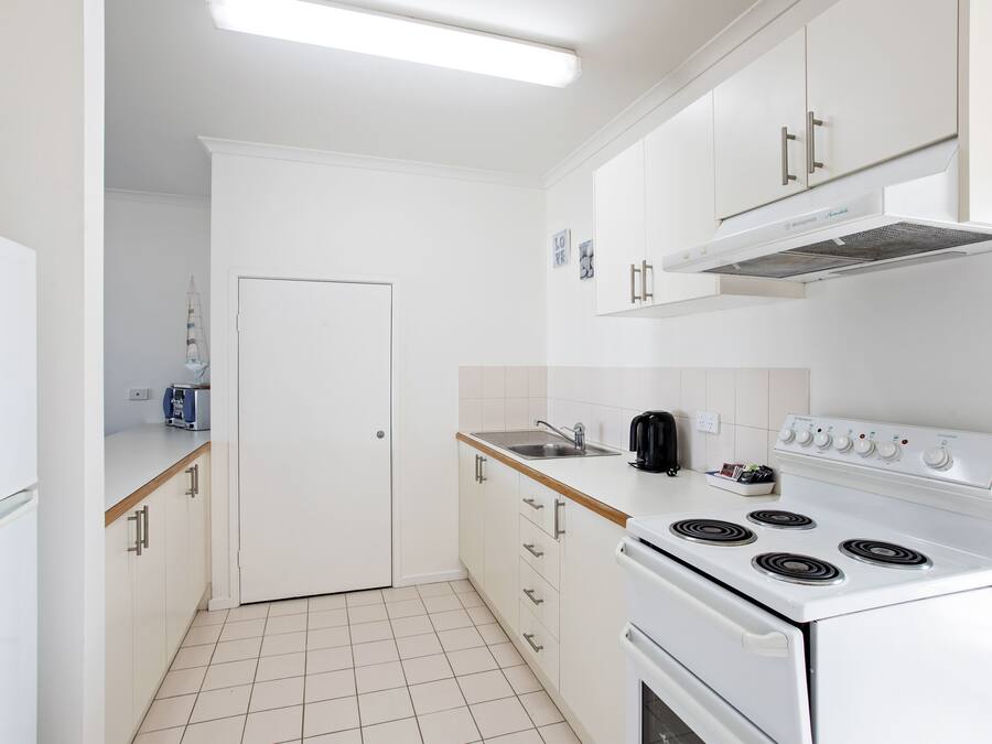 A modern kitchen with white cabinets, a stove, and a sink.