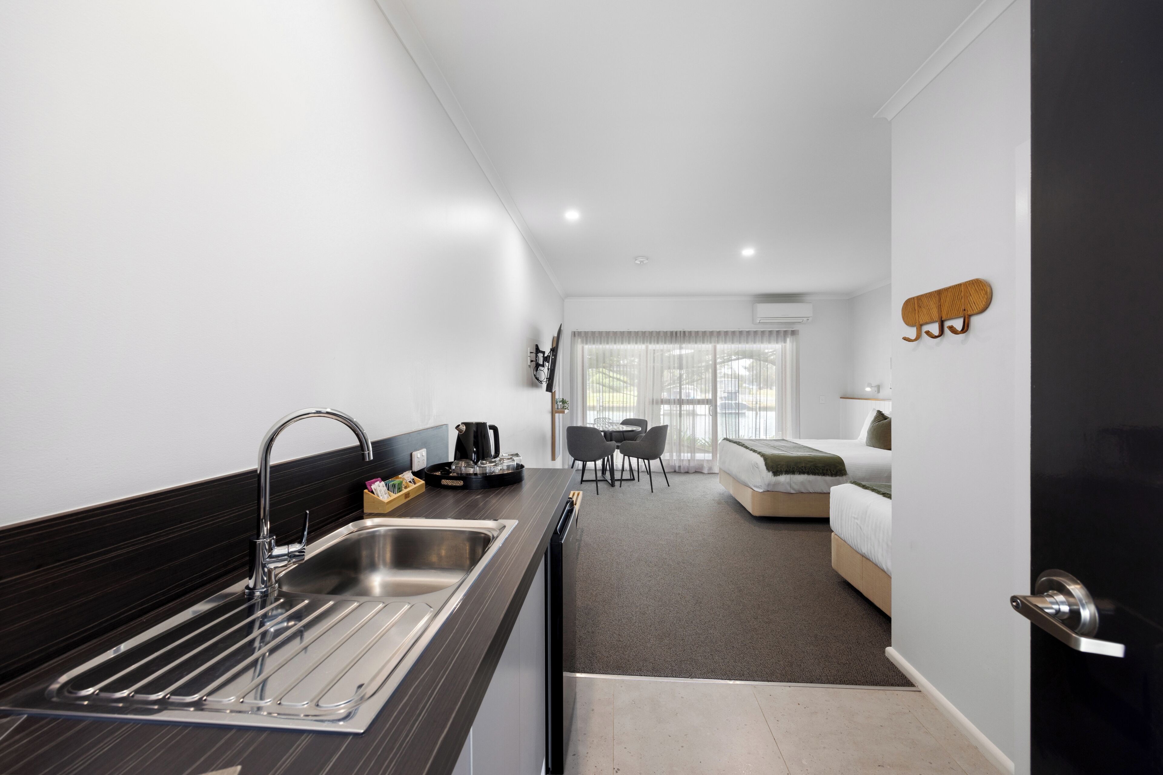Una habitación de hotel moderna con cocina, una mesa de comedor y una cama.