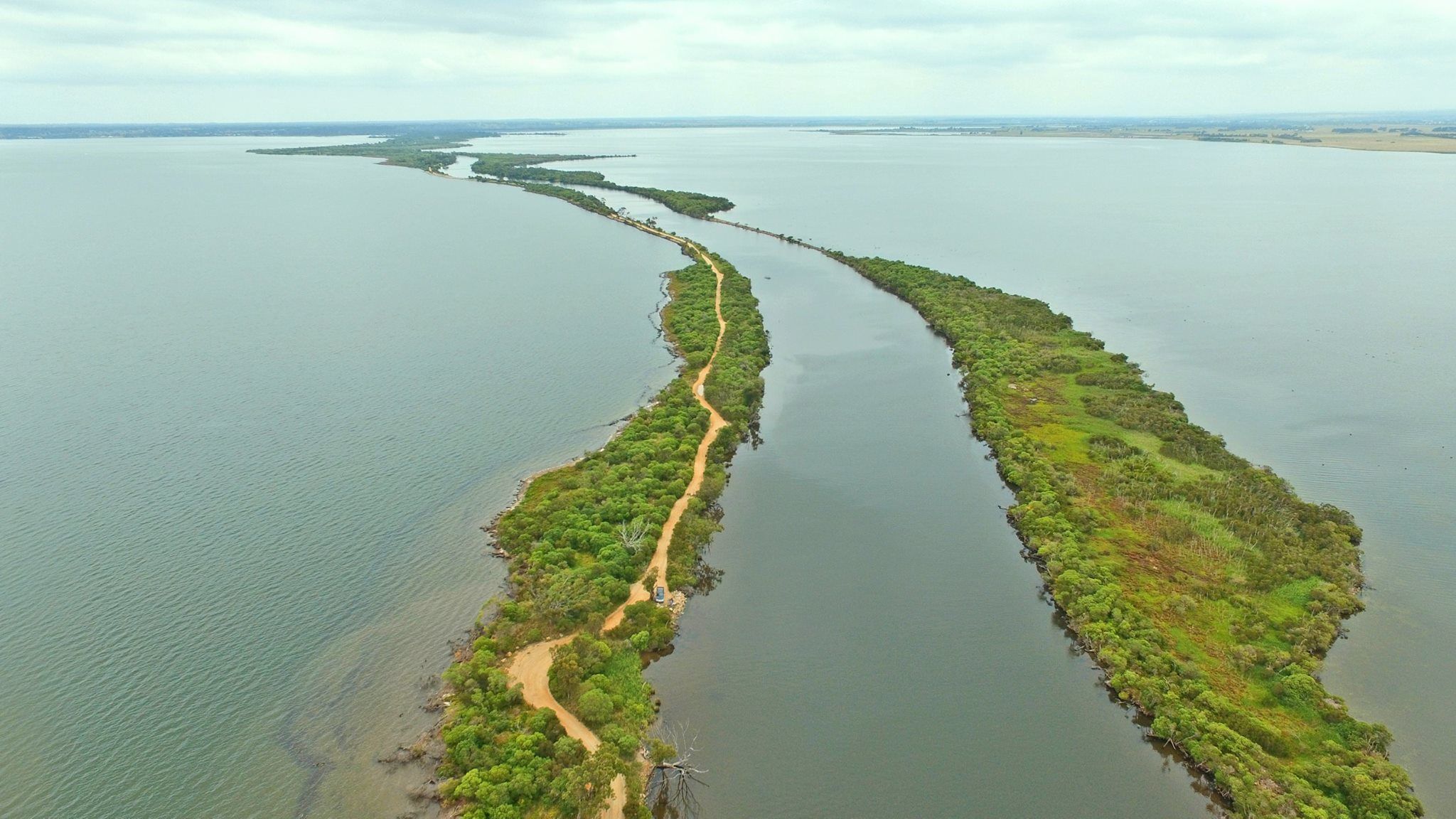 An aerial view of a narrow, elongated island with a winding path.