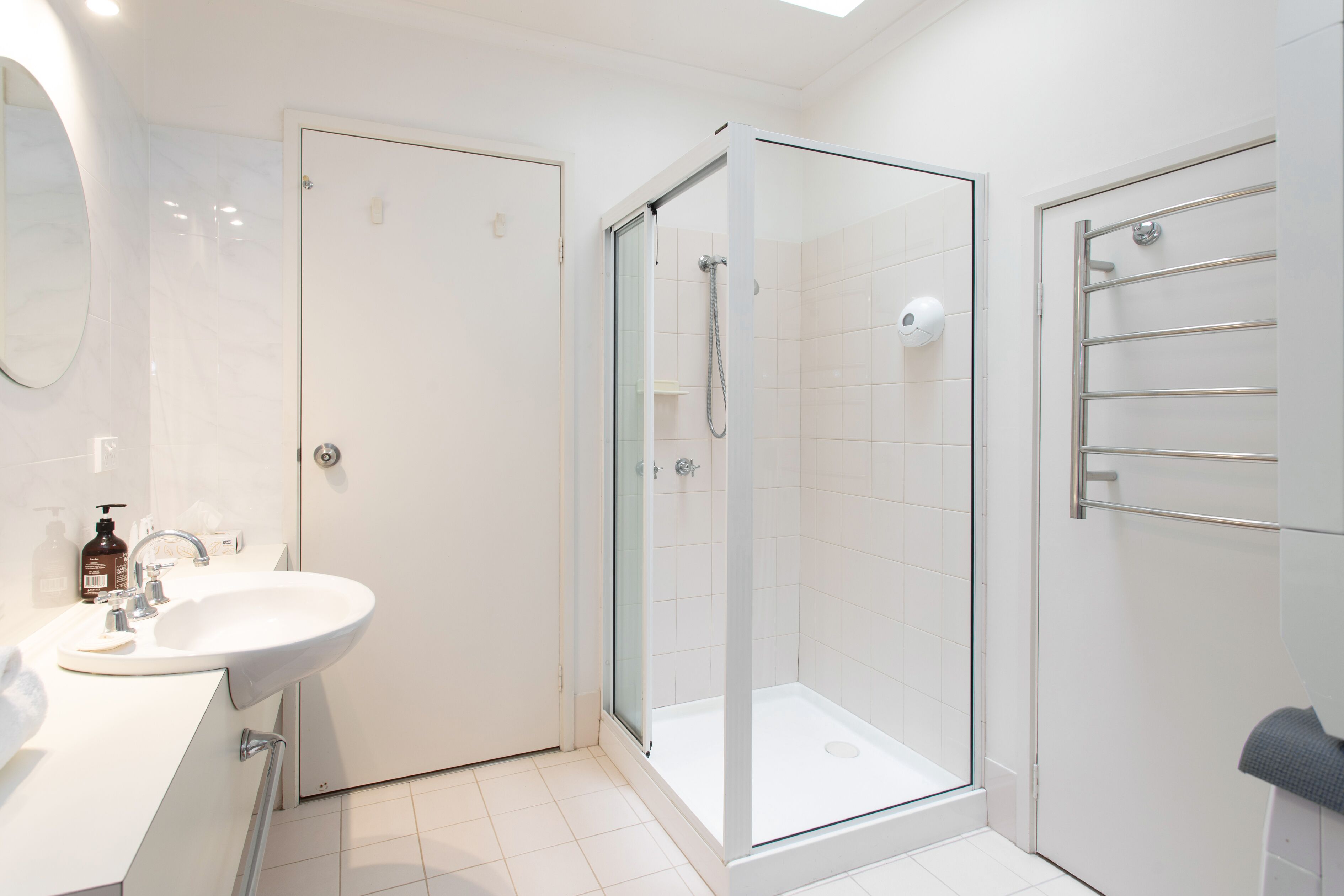 Une salle de bain moderne avec une douche à parois de verre, un lavabo blanc et un porte-serviettes.