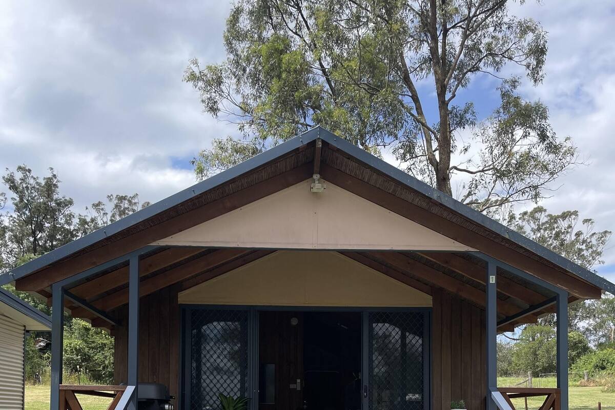 Una cabana de fusta amb un porxo cobert, una entrada amb portes corredisses de vidre i una petita zona d'seients a l'exterior.