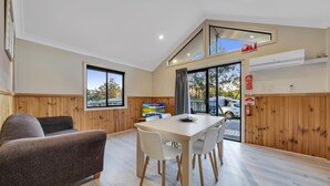 A modern interior with a dining area, wooden walls, and large windows. - Ingenia Holidays Avina (Vineyard)