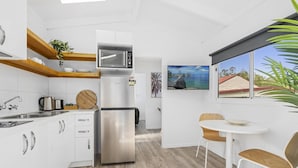 A modern kitchen with white cabinets, stainless steel appliances, and a wooden dining table with chairs. - Ingenia Holidays Avina (Vineyard)