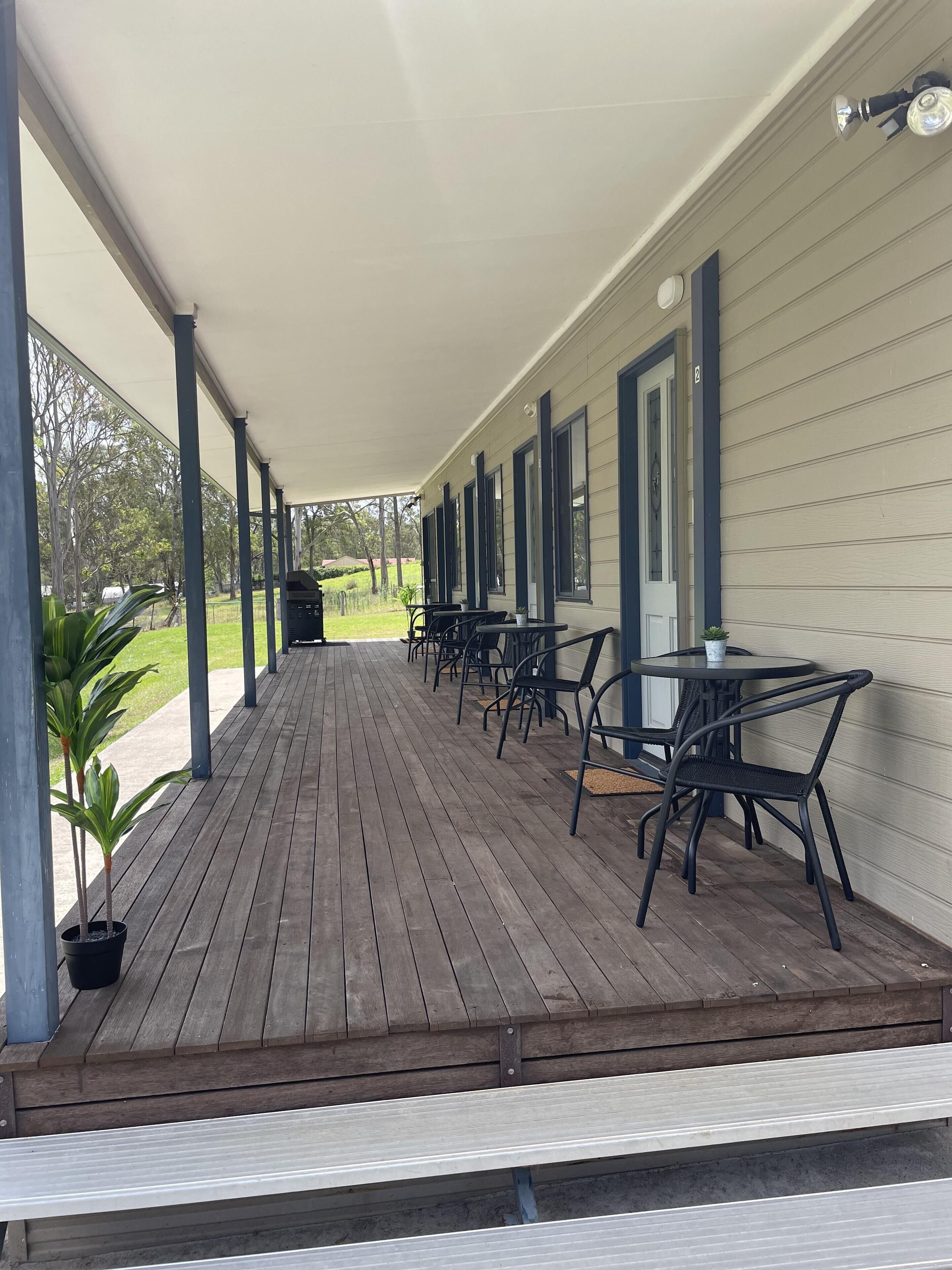 A covered outdoor patio with wooden flooring, metal-framed chairs, and tables.