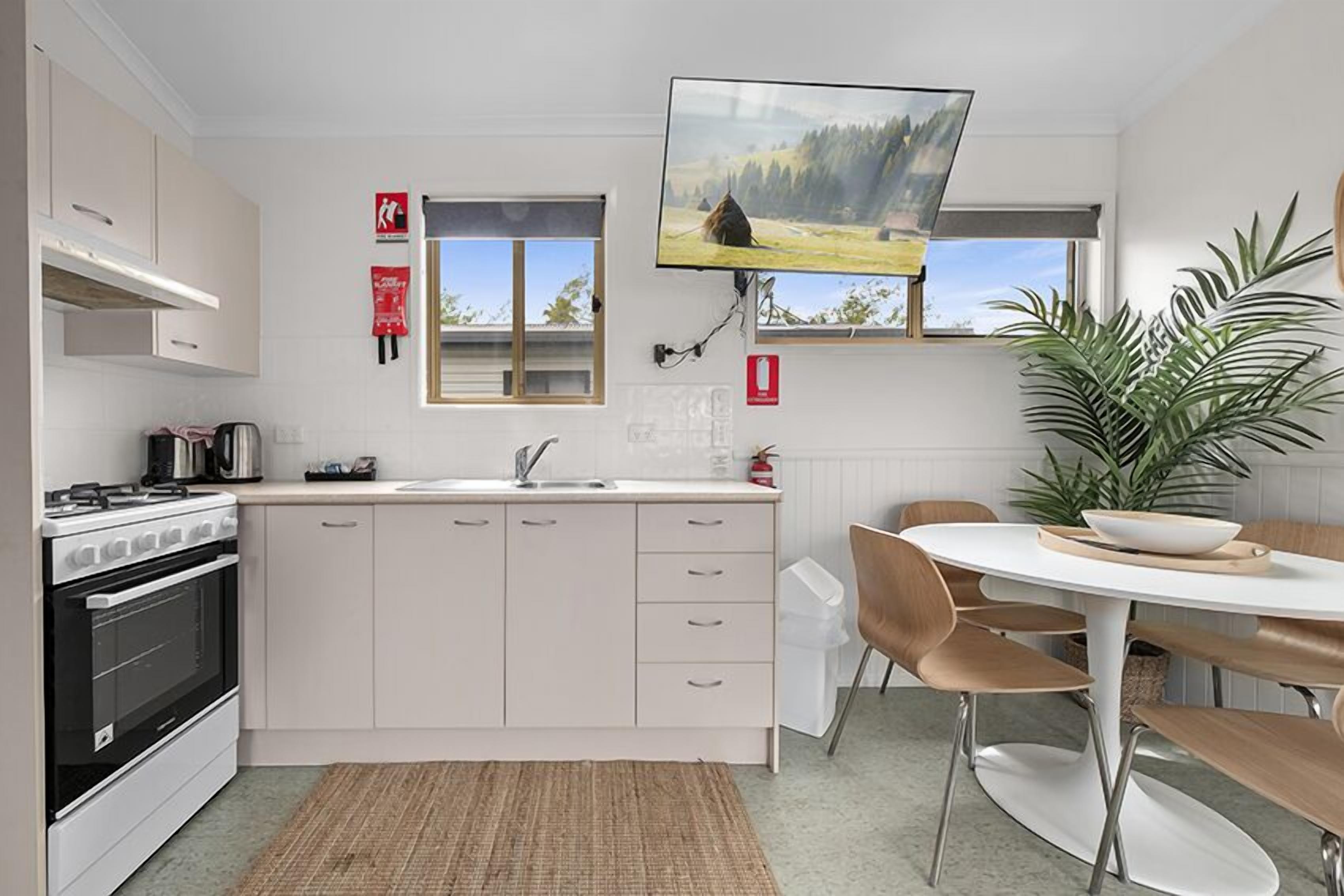 A modern kitchen with white cabinets, a stove, and a dining area with a round table and chairs.