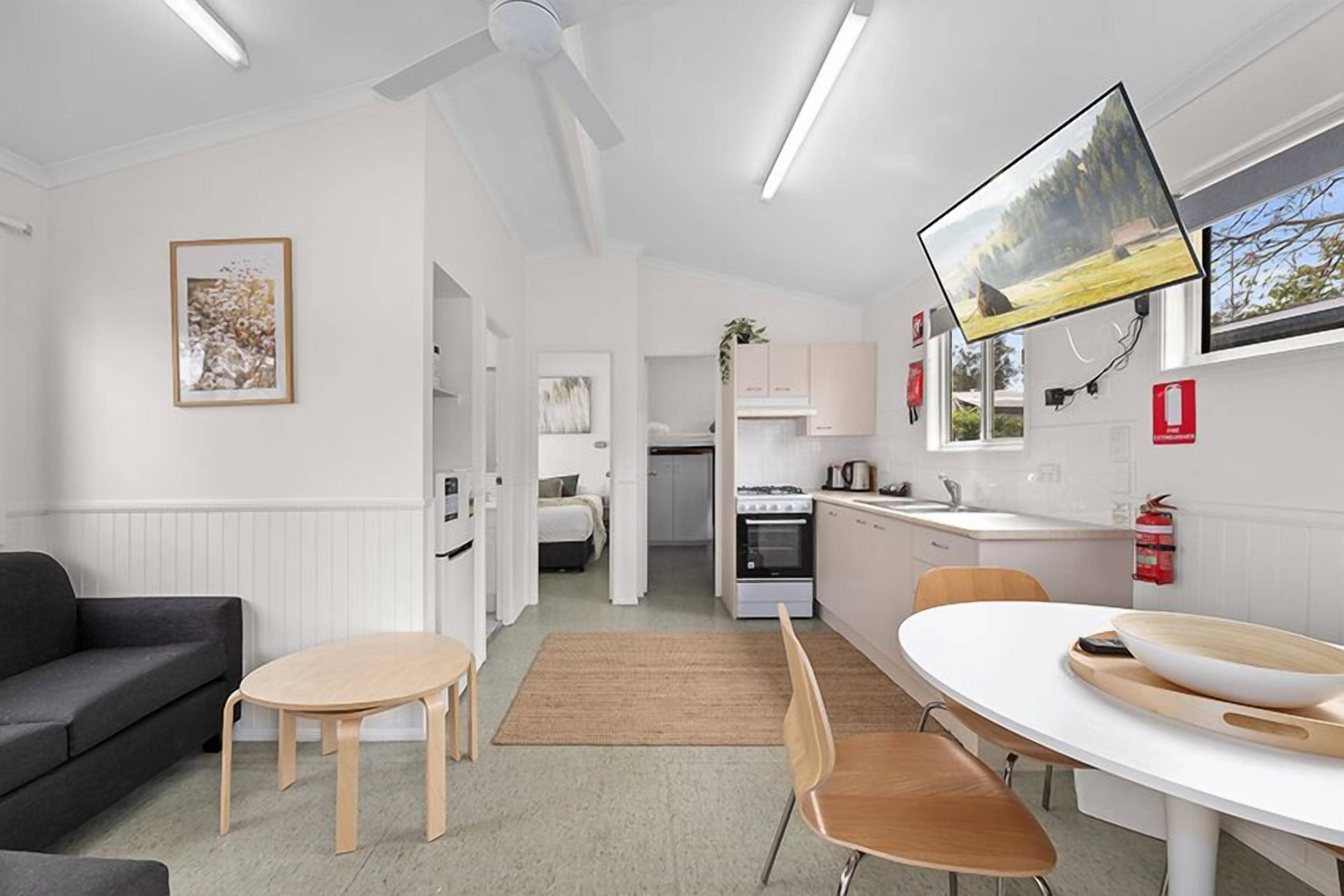 Een moderne keuken met witte kasten, een fornuis en een eethoek met een witte tafel en stoelen.
