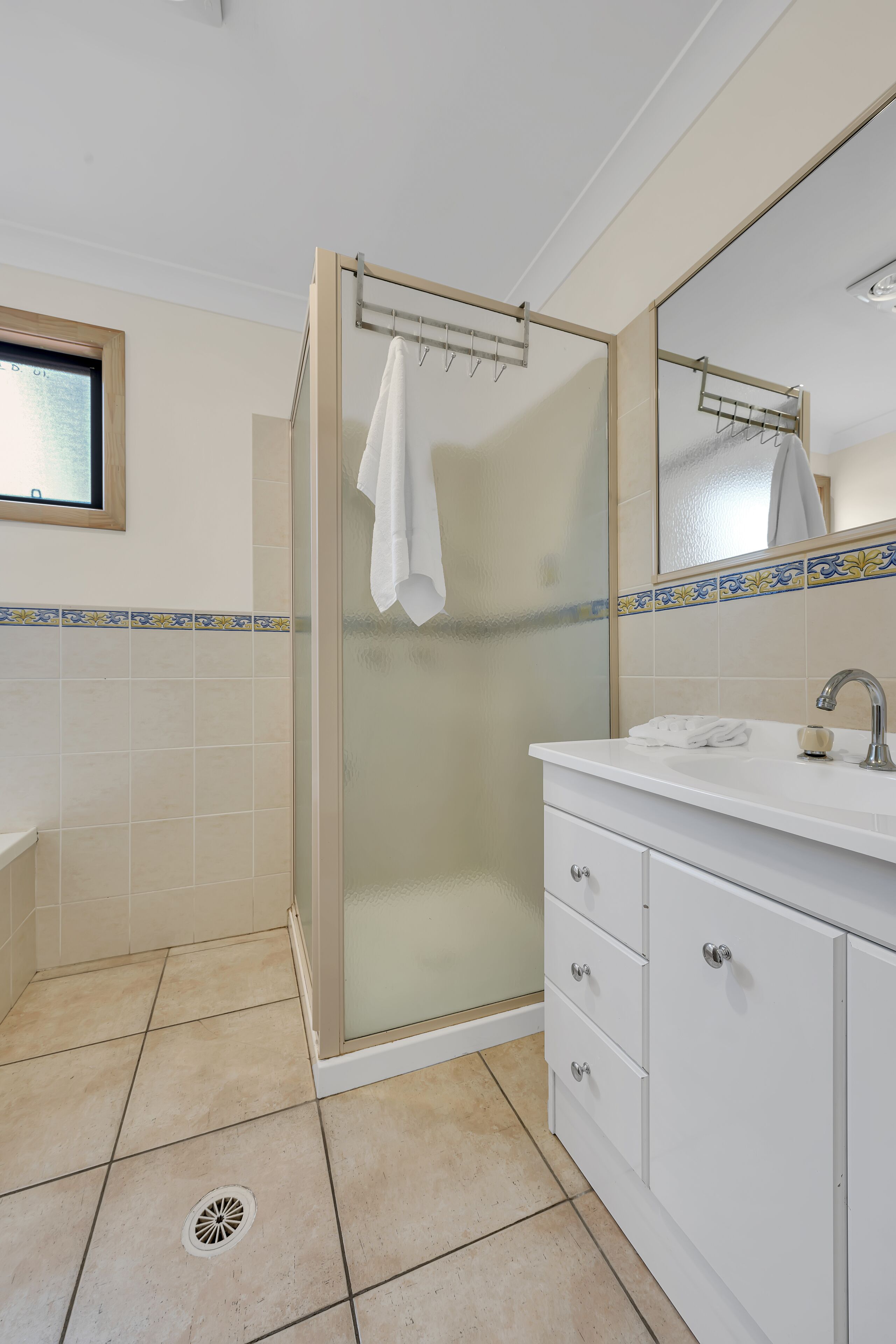 A bathroom with a glass-enclosed shower, a white sink, and a mirror above the sink.