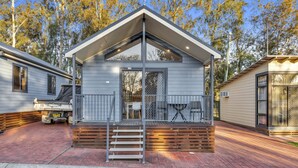 A single-story mobile home with a front porch, a small deck, and a visible garage. - Ingenia Holidays Avina (Vineyard)