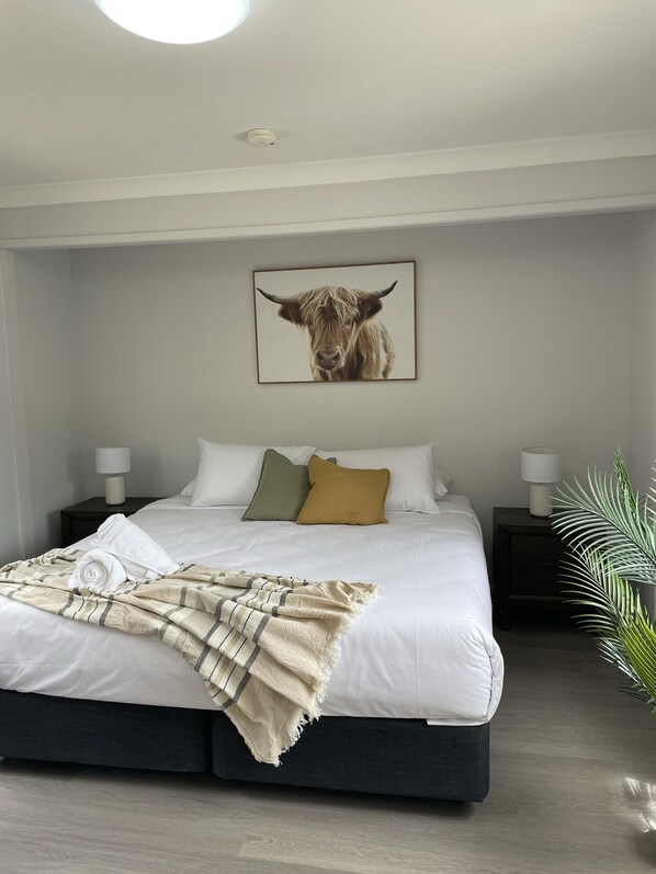 A modern bedroom with a large bed, a framed animal print on the wall, and a plant beside the bed. - Ingenia Holidays Avina (Vineyard)