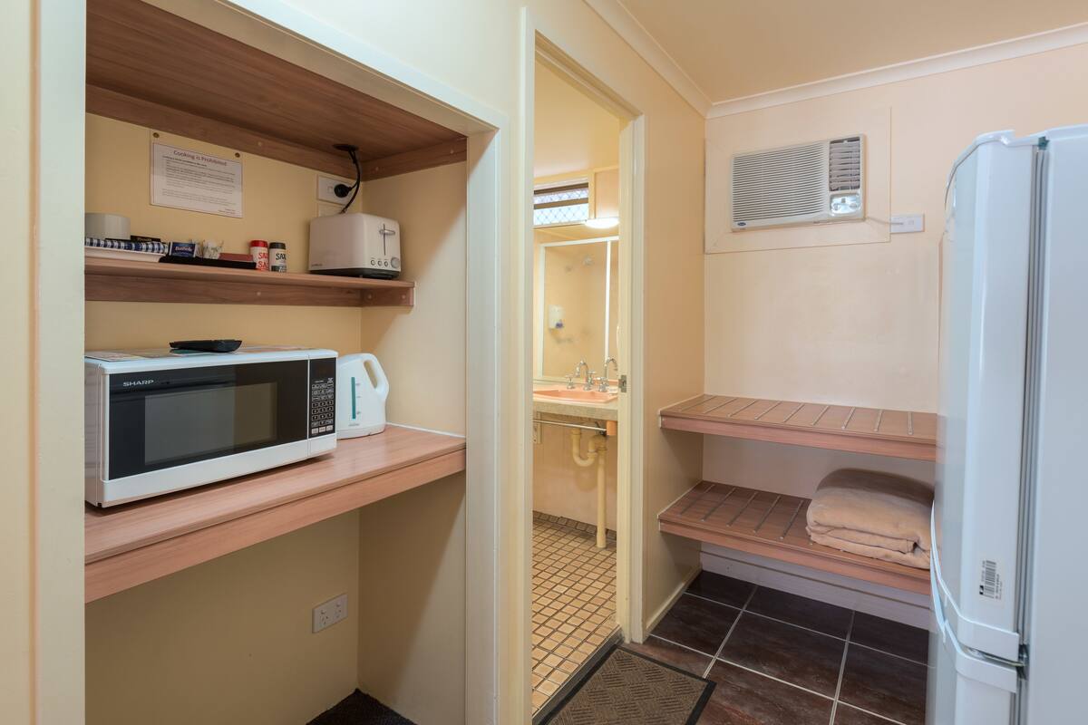 Una cocina compacta equipada con microondas, refrigerador y lavamanos.