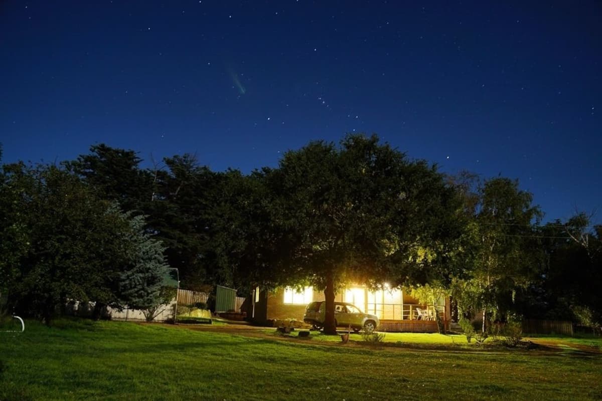 A house with a well-lit front porch, a parked car, and a lawn.