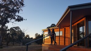 A modern house with a wooden exterior, a staircase leading to a deck, and a clear view of the surrounding trees. - Curringa Farm (Hamilton)