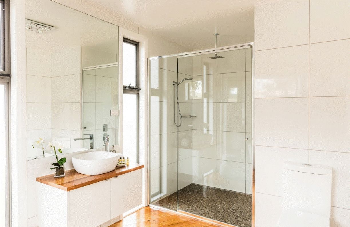 A modern bathroom with a glass-enclosed shower, a white sink, and a wooden vanity.