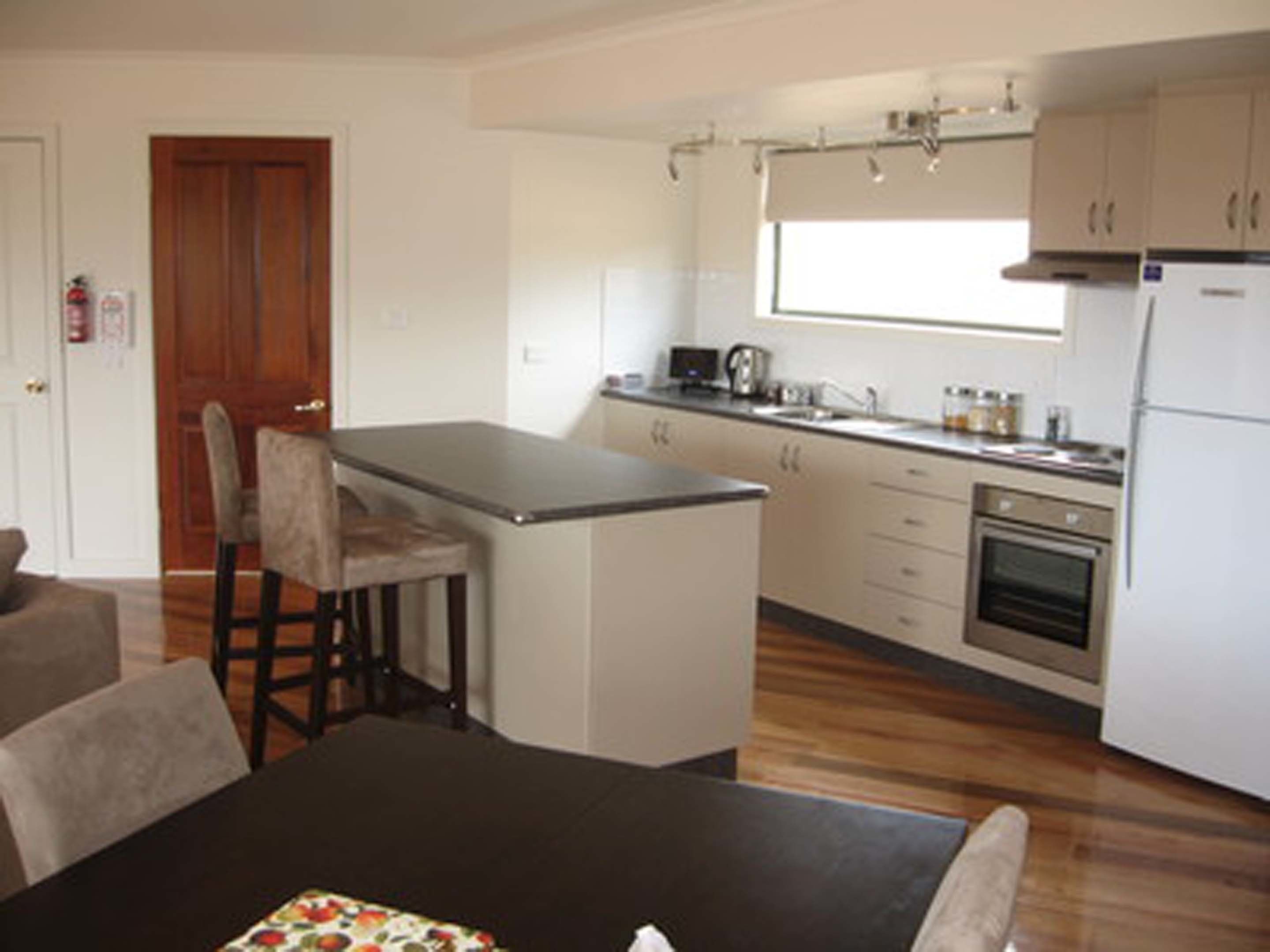 Una cocina compacta con una isla central, un comedor con mesa y sillas, y un refrigerador.