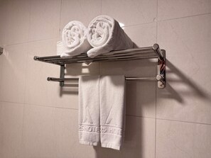 A metal towel rack with two rolled towels and one folded towel against a tiled wall. - A25 Hotel - 45B Giang Vo (Hanoi)